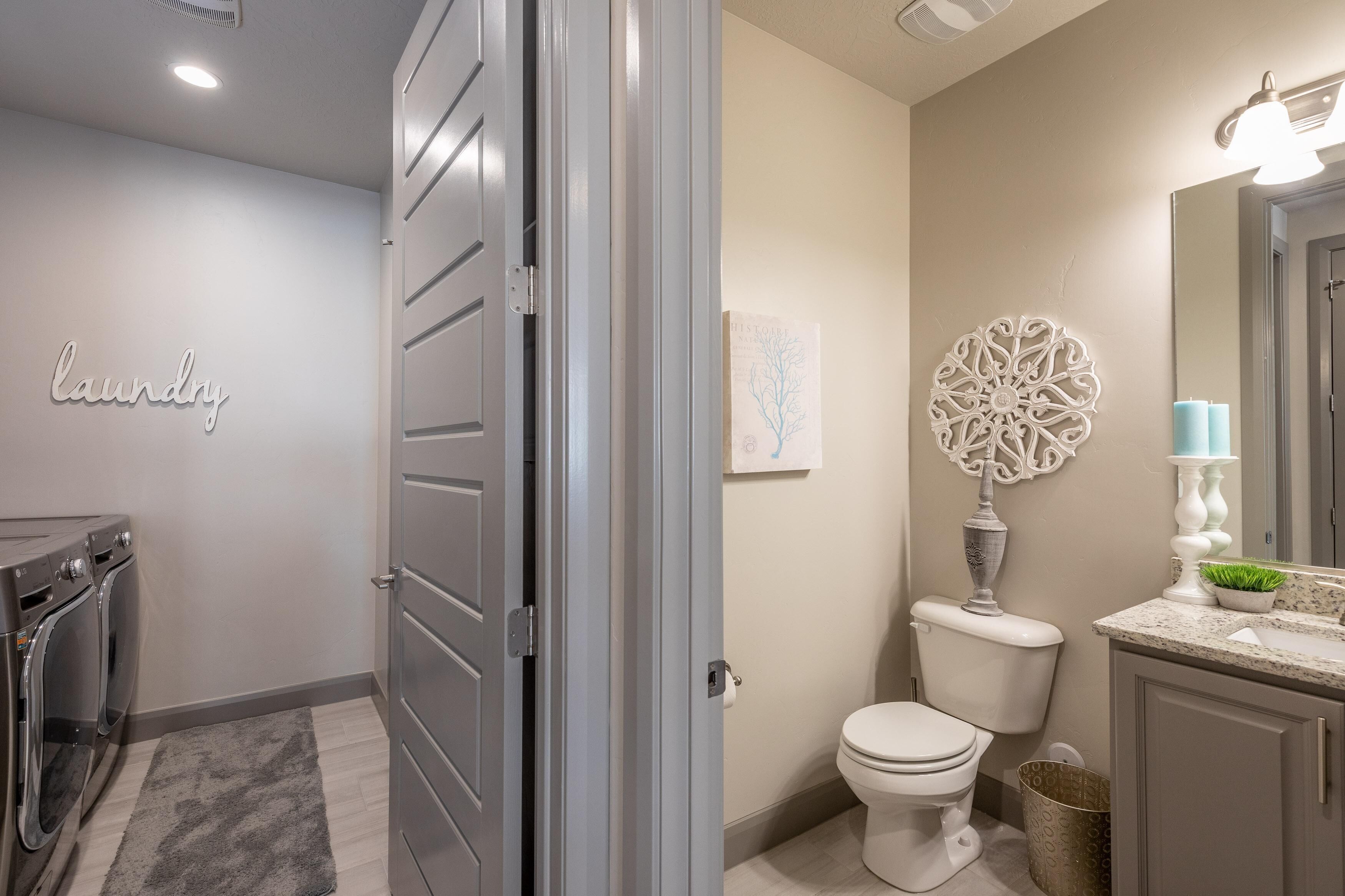 Un baño moderno con inodoro, lavamanos y arte decorativo en la pared.