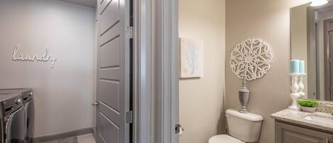 Un baño moderno con inodoro, lavamanos y arte decorativo en la pared.