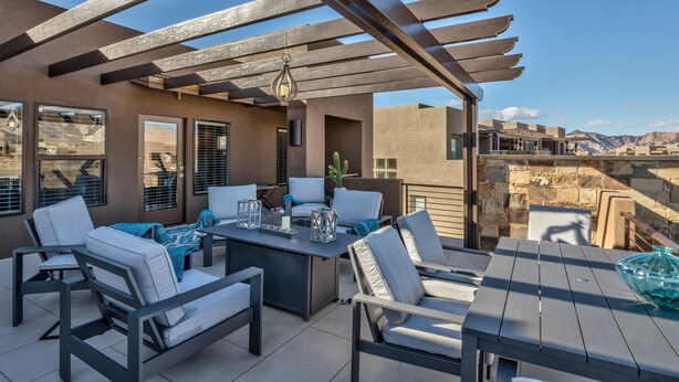 An outdoor patio with a pergola, seating, and a view of the mountains. - Fun At The Ledges (St. George)