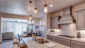A modern kitchen with granite countertops, stainless steel appliances, and pendant lighting. - Fun At The Ledges (St. George)