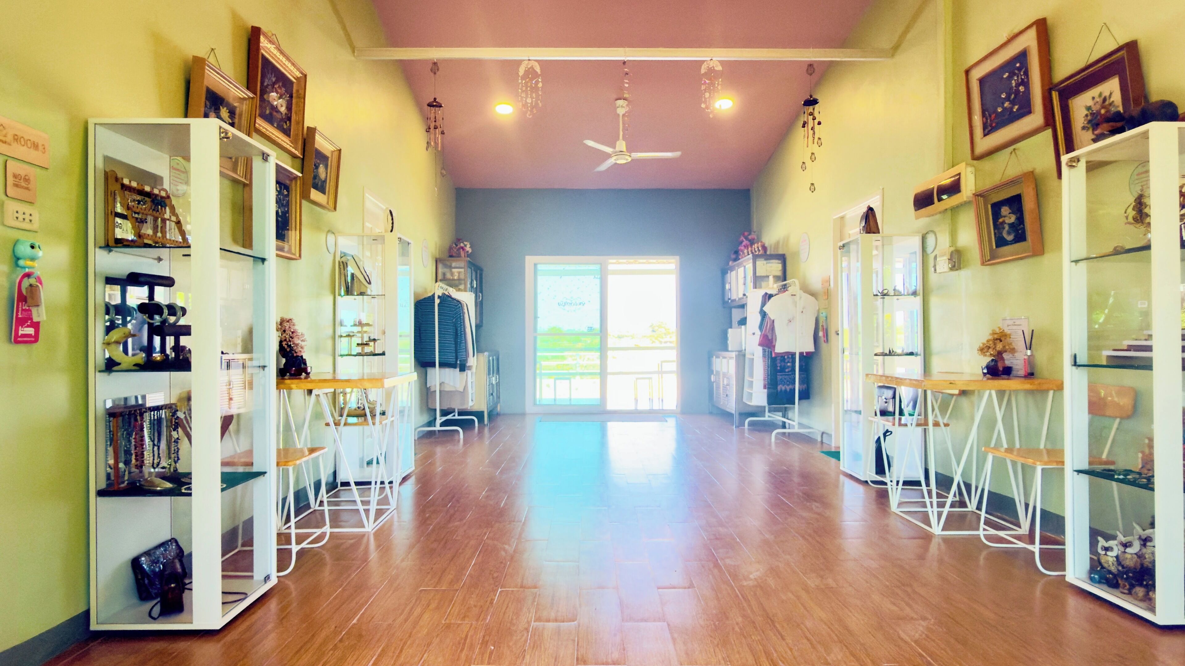A spacious salon with wooden floors, mirrored walls, and ceiling fans.