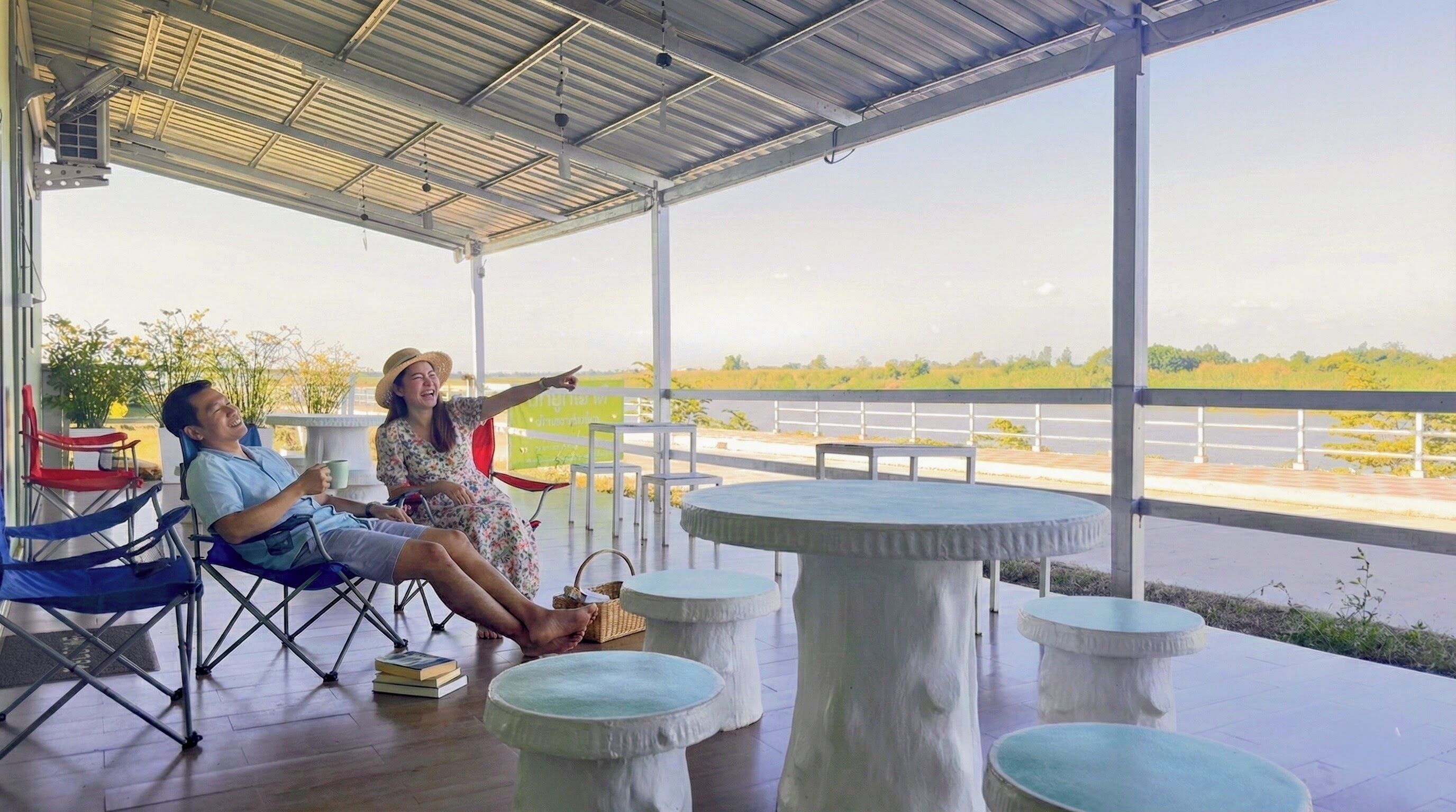 Un espacio de estar techado al aire libre con mesas y sillas, con vista a un río.