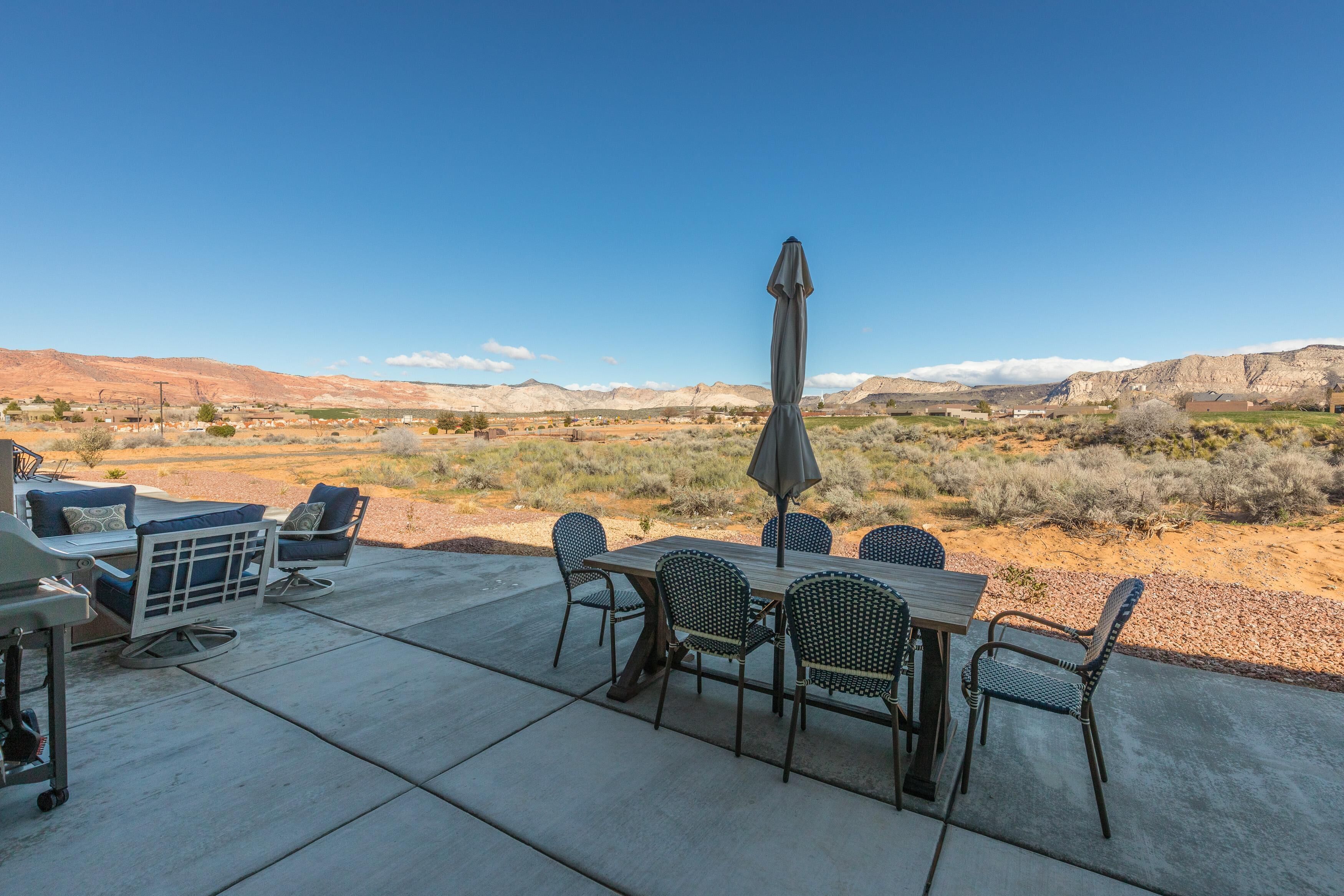 Une terrasse extérieure avec une table et des chaises, un barbecue et une vue sur un paysage désertique.