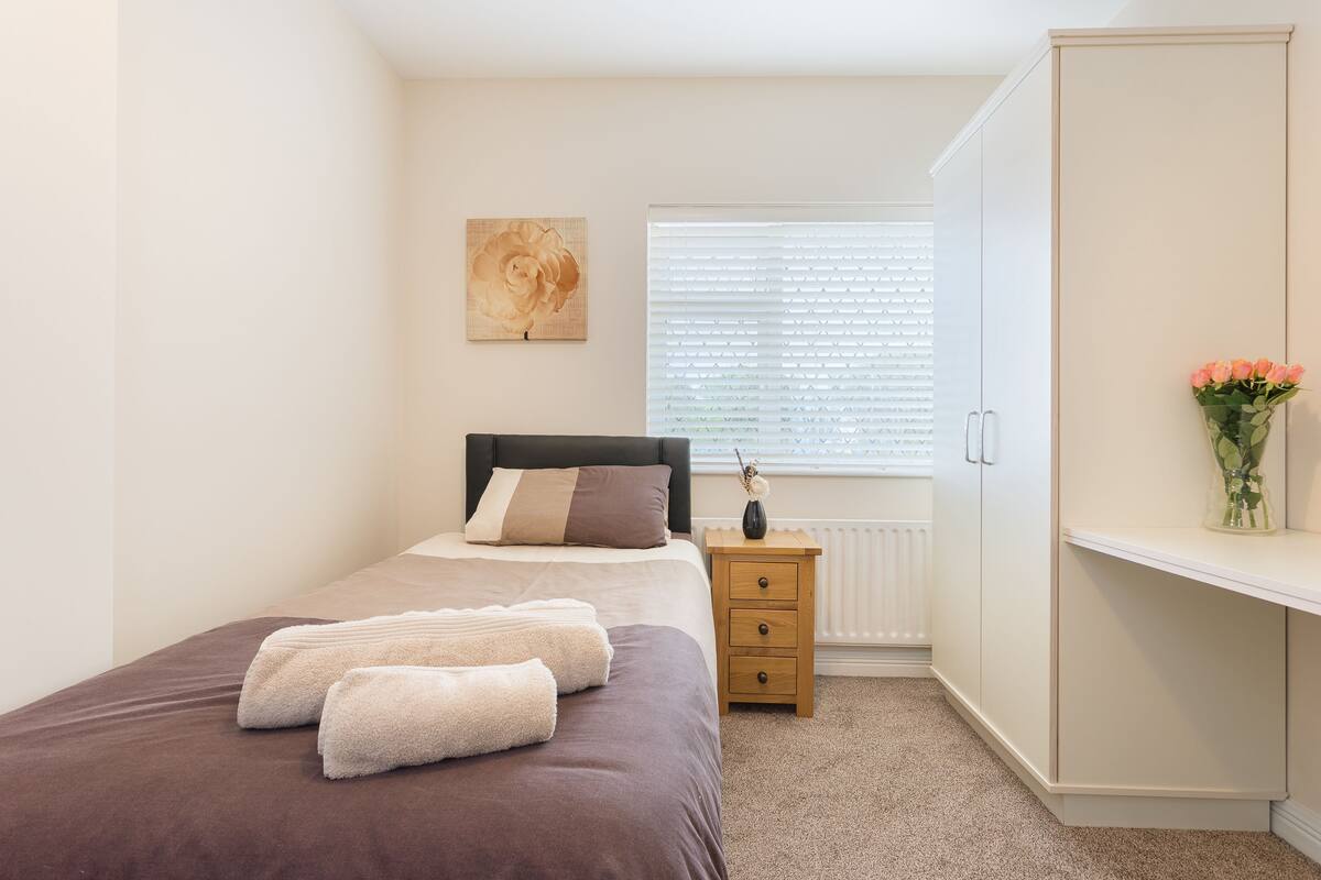 A neatly arranged bedroom with a bed, bedside table, and a wardrobe.