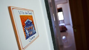 Ein gerahmtes Bild der Villa dei Templi, darunter der Schriftzug 'Cerce', an einer Wand befestigt.