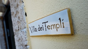 Ein Schild mit dem Schriftzug 'Villa dei Templi' an einer Wand.