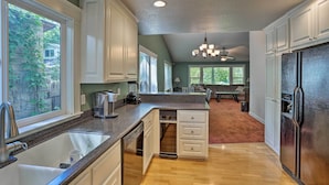 A kitchen with white cabinets, a granite countertop, a stainless steel refrigerator, and a dishwasher. - Spacious Downtown Chico Home ~ Half Mile to CSU! (Chico)