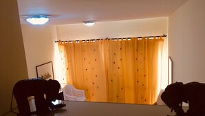 Una habitación con una cama, una mesita de noche, una lámpara y una ventana con cortinas.