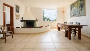 A spacious room with a fireplace, a dining table, and a large window. - La Bodega – On a Volcano with Piano, Sea Views, Private Terrace & Wi-Fi (Haria)