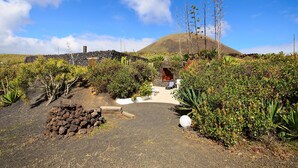 A garden pathway leading to a stone structure with a view of a mountain. - La Bodega – On a Volcano with Piano, Sea Views, Private Terrace & Wi-Fi (Haria)