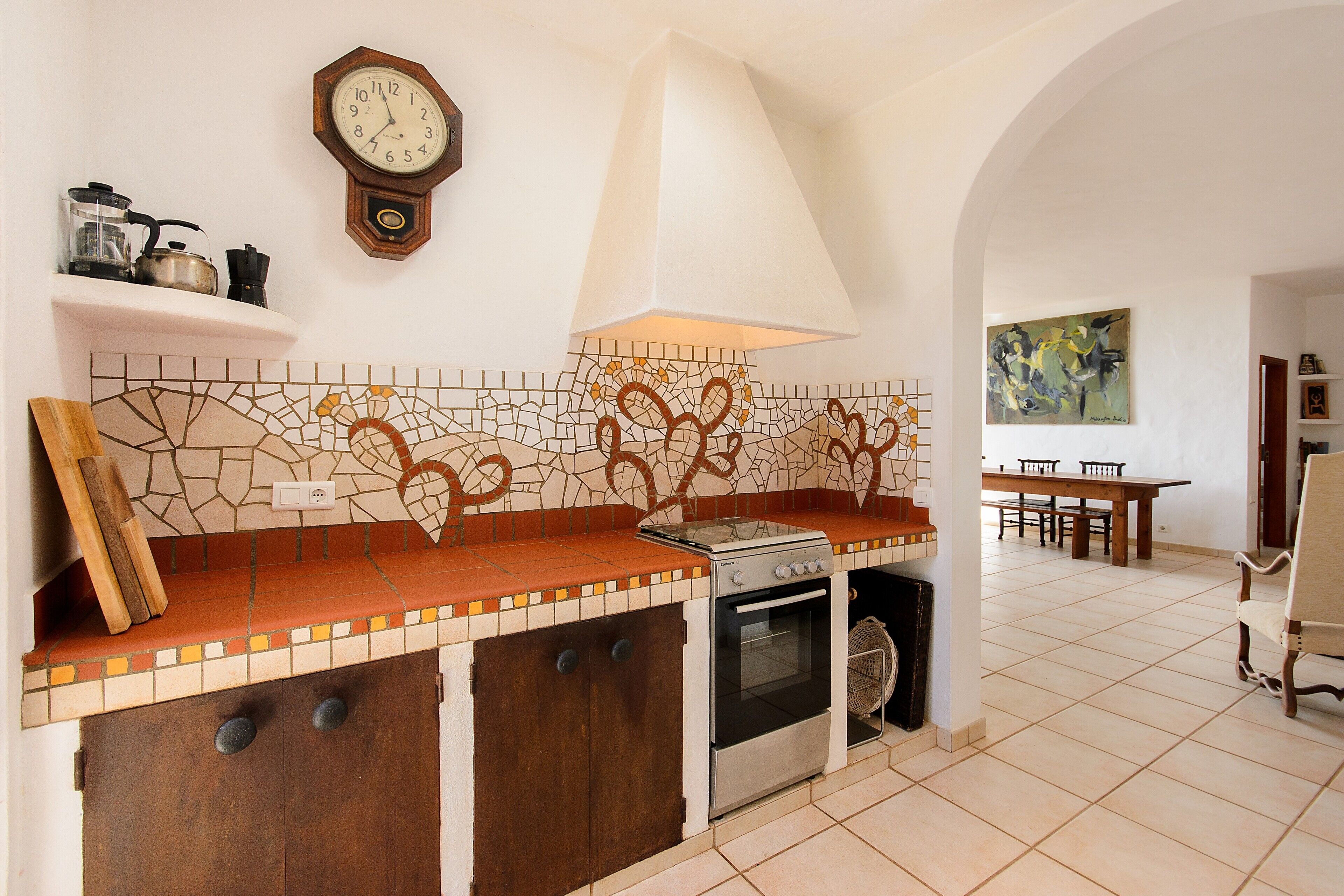 Une cuisine avec un mur recouvert de carreaux, une cuisinière et une horloge au mur.