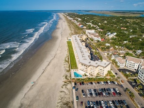 Ett flygbildsfoto av ett hotell vid kusten, med läge nära stranden, parkeringsmöjligheter och en swimmingpool.