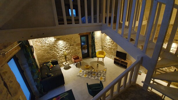 A cozy living area with a stone wall, a staircase, and a seating arrangement including a sofa, chairs, and a coffee table. - Stone country house (Saint-Remy)