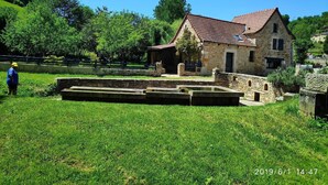 A stone building with a red-tiled roof, surrounded by a grassy area and trees. - Stone country house (Saint-Remy)