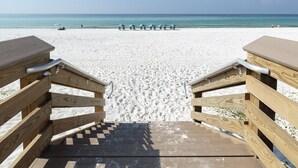 Una pasarela de madera que conduce a una playa arenosa con vista despejada al océano.