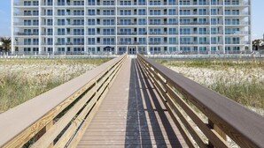 Un hotel moderno con un largo paseo de madera que conduce a la entrada.