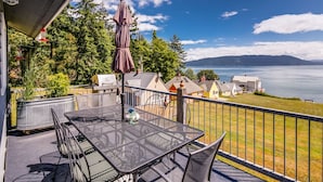 Un balcon avec une table et des chaises, offrant une vue panoramique sur un lac et des maisons.