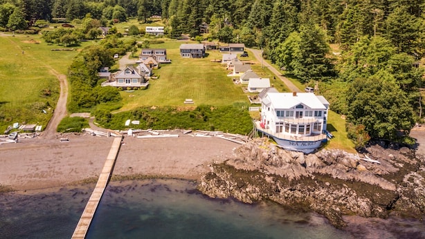 Une propriété située sur la côte, comprenant une grande maison, un quai et une zone boisée.