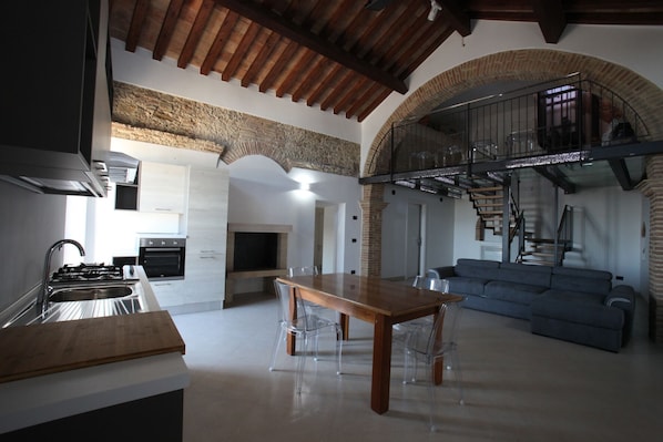 Una cocina moderna con comedor, una escalera y una sala de estar con sofá azul.