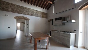 A spacious kitchen with a wooden table and chairs, a modern stove, and a stone wall.