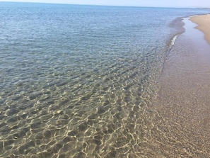 Una playa con aguas poco profundas y cristalinas, y una orilla arenosa.