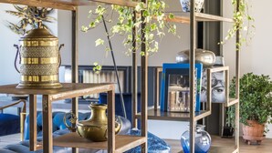 A room with a wooden table, a brass lamp, and shelves with books and decorative items.