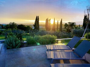 A terrace with lounge chairs, a view of the sunset, and surrounding greenery. - Charming rental villa, magnificent views of Lake Garda, park and private pool (Lazise)