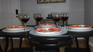 Une table à manger dressée avec des assiettes et des verres à vin, des chaises et un élément décoratif mural.