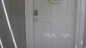 Une porte blanche avec une pancarte indiquant «Bienvenue» et une plaque portant le numéro de la maison.