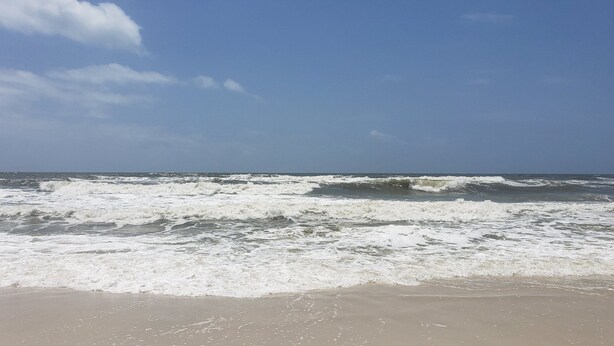 Une plage où les vagues se brisent sur le rivage sous un ciel dégagé.