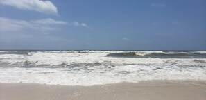 A beach with waves crashing onto the shore under a clear sky.