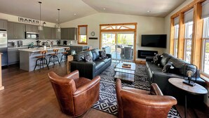 A spacious living area with a kitchen, a dining area, and a seating area with leather sofas and chairs. - I'm Your Huckleberry at Lake Chelan Lookout Vacation Rentals (Chelan)