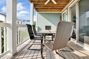 A covered patio with a table and chairs, a ceiling fan, and a sliding glass door. - Modern, upscale townhouse, 3 min walk to the beach, 5 bedrooms/4 full baths! (Kure Beach)