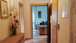 Un passadís amb un armari de fusta, un quadre i una catifes amb motius.