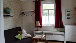 Un saló acollidor amb un sofà fosc, una taula de fusta petita, un globus a la paret i una finestra amb cortines vermelles.