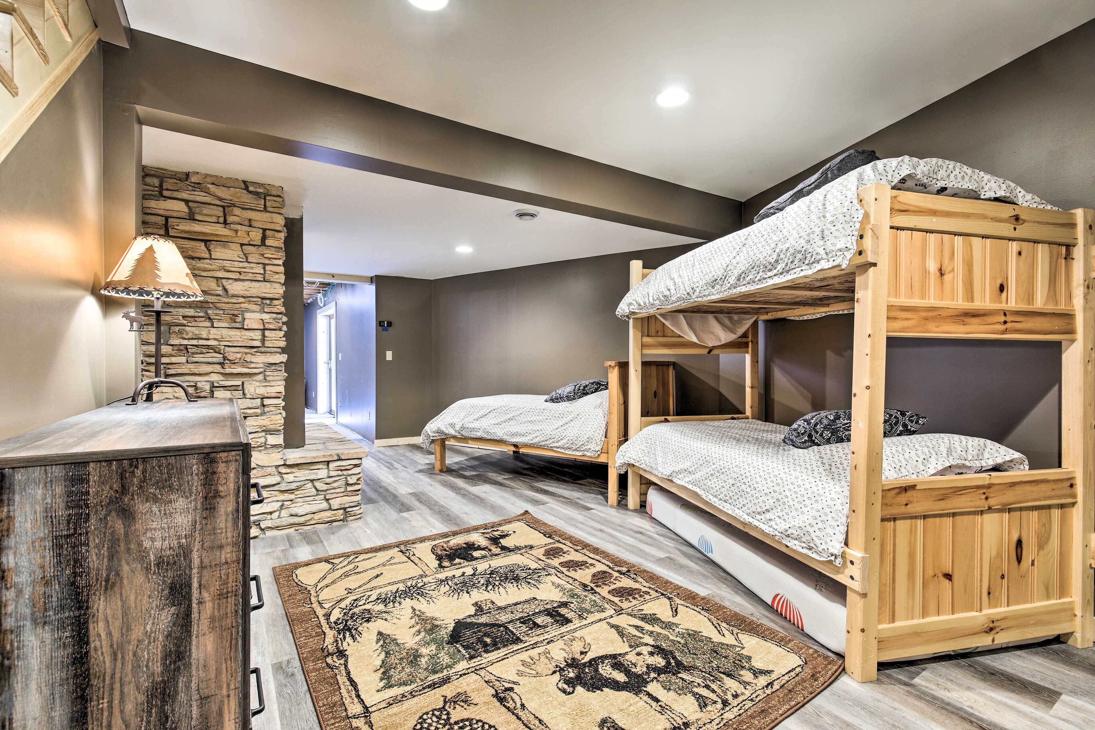 A room with two bunk beds, a wooden dresser, a stone wall, and a patterned rug.