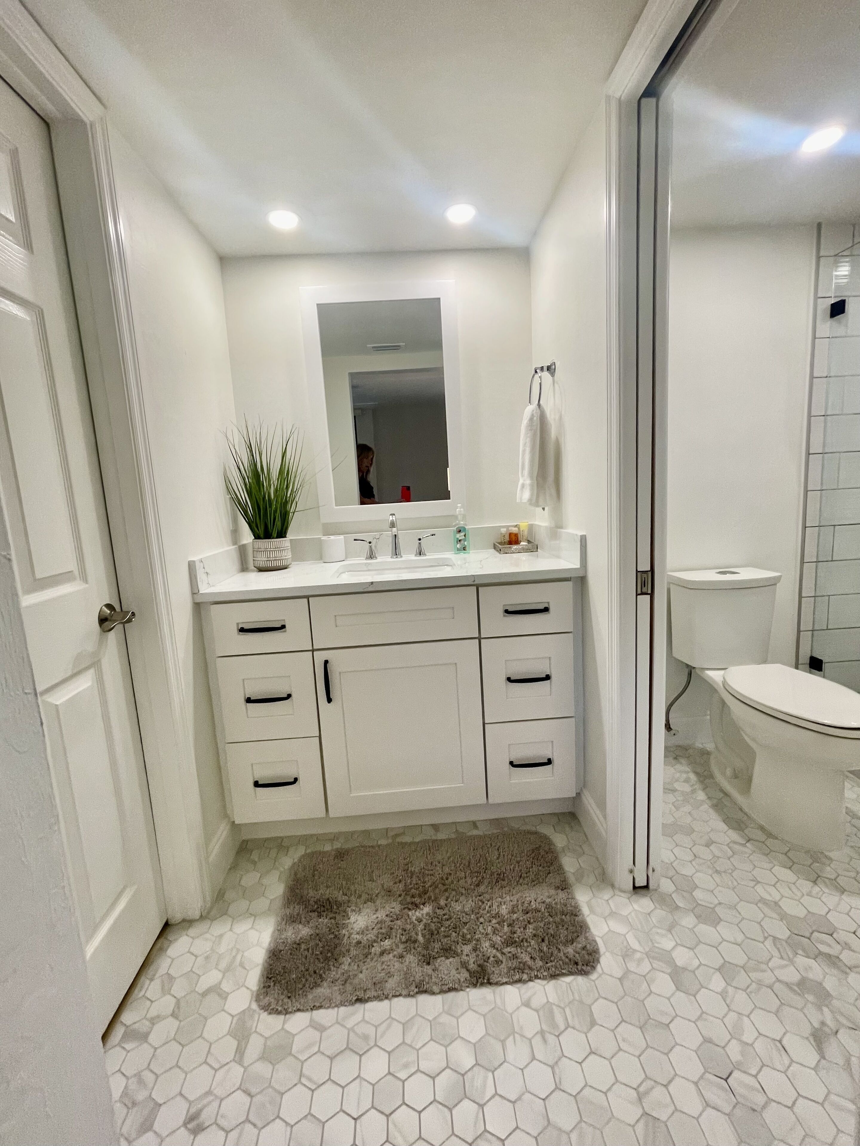 Un baño con tocador blanco, un espejo, un inodoro y una zona de ducha.
