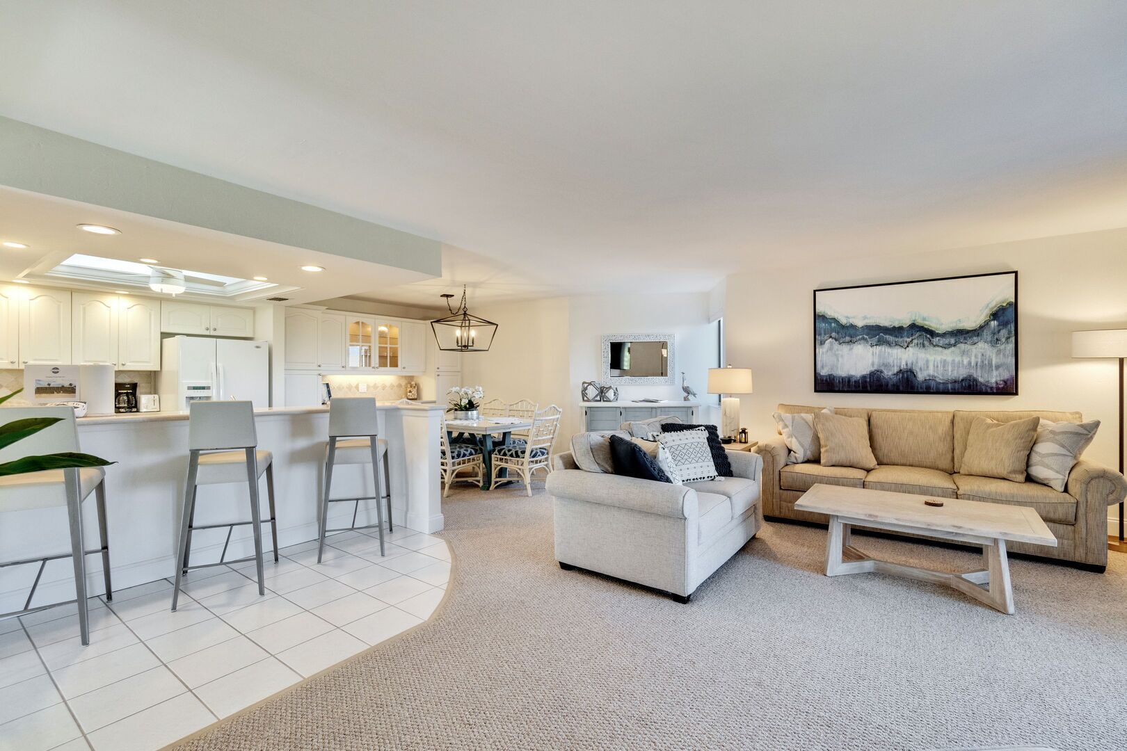A modern living room with a white sofa, a coffee table, and a dining area with a white table and chairs.