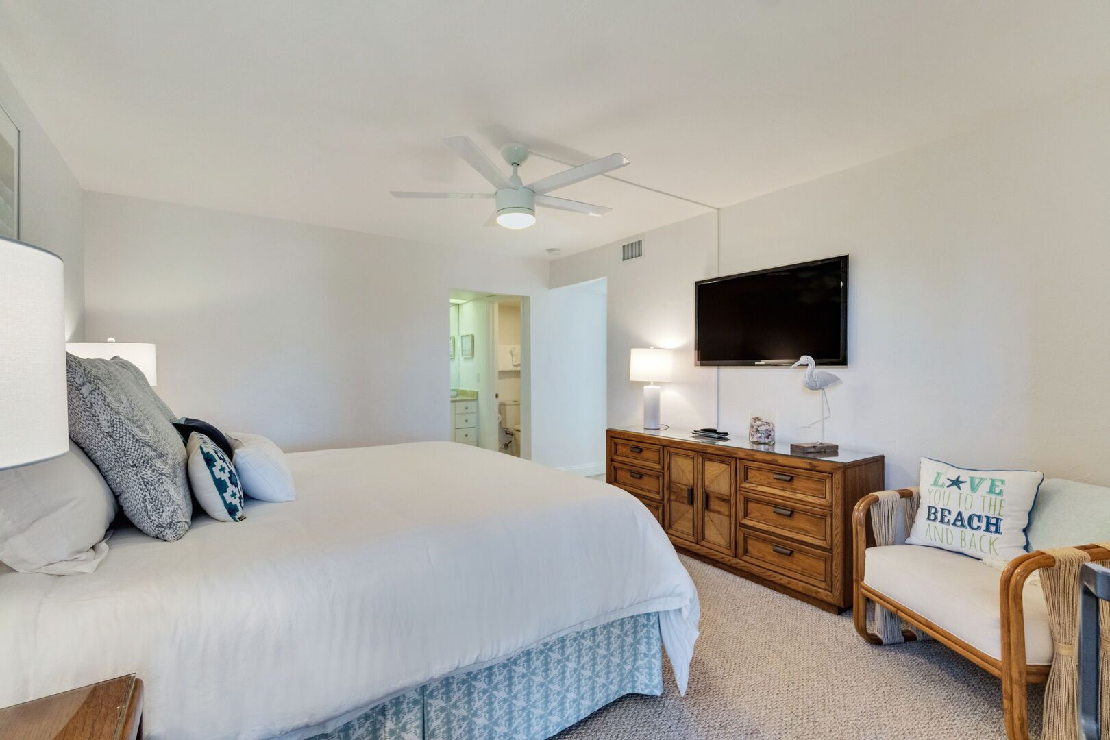 Une chambre à coucher avec un grand lit, une commode en bois, un téléviseur et une chaise.