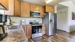 Eine Küche mit Holzausstattung, einem Edelstahlkühlschrank, einer Mikrowelle und einem eingebauten Backofen.