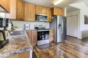 Una cocina con armarios de madera, un refrigerador de acero inoxidable, un microondas y un horno empotrado.