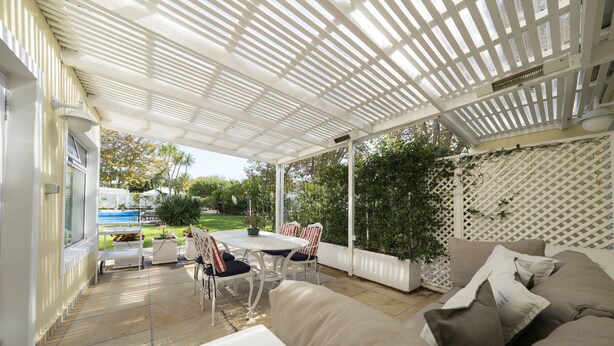 A covered outdoor patio with a table and chairs, a sofa, and a view of the garden. - 4-STAR-Apartment (AA Superior rated) at the Constantia Wine Route / Kapstad (Constantia)