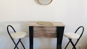 A small wooden table with a mirror above it, flanked by two black chairs with white furry seats. - Rent studio per week (Eaux-Vives)