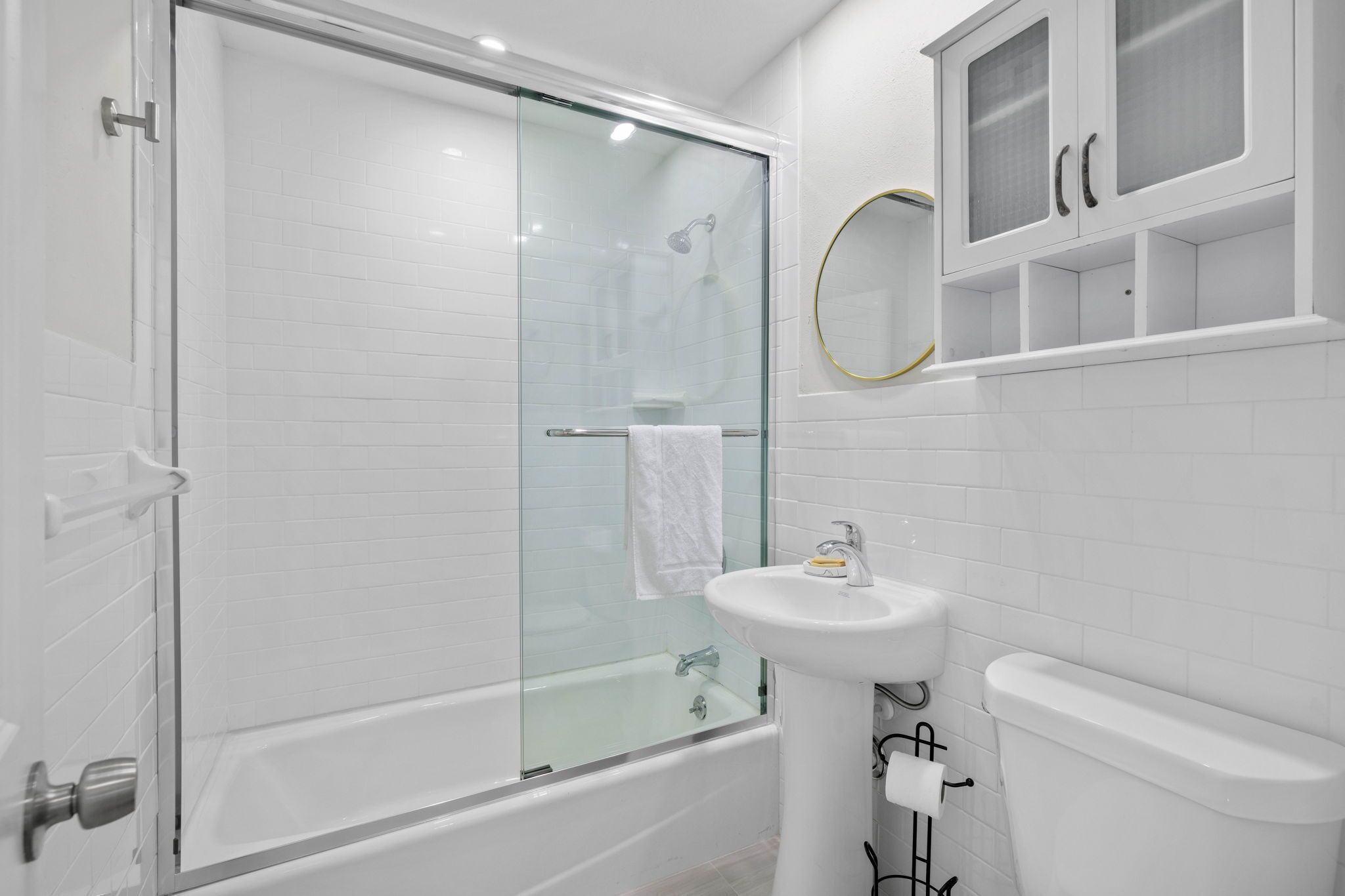 A modern bathroom with a glass-enclosed shower, a white sink, and a toilet.