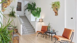 Ein modernes Interieur mit einer Treppe, zwei Ledersesseln, einem Tisch mit Globus und einigen Blumentöpfen.