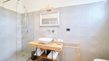 Une salle de bain moderne avec une douche à parois de verre, un meuble-lavabo en bois doté d’un grand évier et un miroir au-dessus.