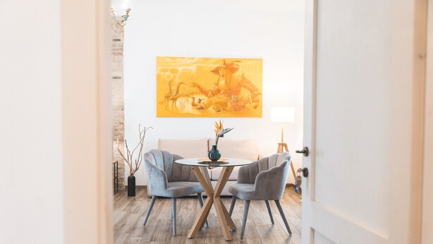 Ein Essbereich mit einem runden Tisch, zwei Stühlen, einem Bild an der Wand und einer Lampe.
