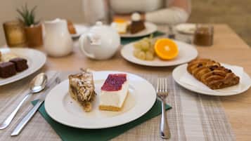 A table set with various desserts, including a cheesecake, a fruit platter, and a pastry.