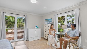 Una habitación amplia con ventanas grandes, un comedor y un televisor sobre un mueble.