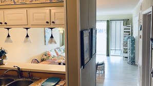 A kitchen with a dishwasher, sink, and a dining area with a table and chairs. - A Place at the Beach resort Family Fun!150'Waterslide, indoor pool&Putt Putt (Atlantic Beach)